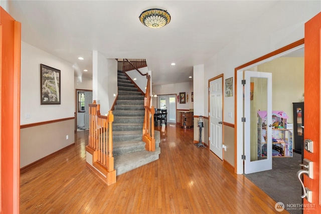 foyer with wood-type flooring, stairs, baseboards, french doors, and recessed lighting