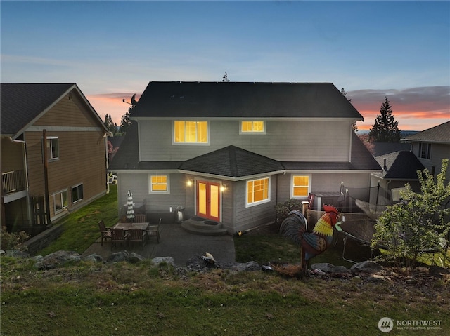back of property at dusk with a patio, a lawn, and entry steps