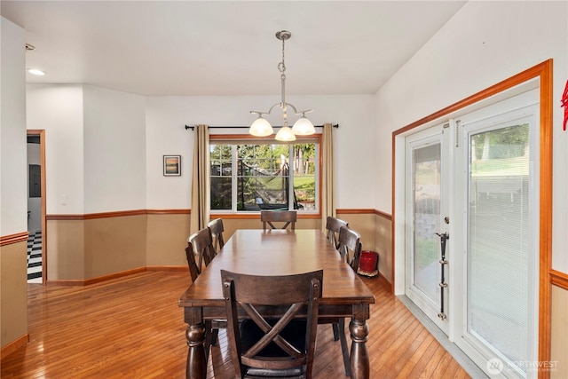 dining space featuring a chandelier, hardwood / wood-style flooring, healthy amount of natural light, and baseboards