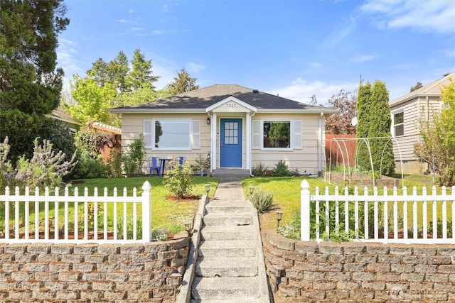 bungalow-style house featuring a shingled roof, fence, and a front yard