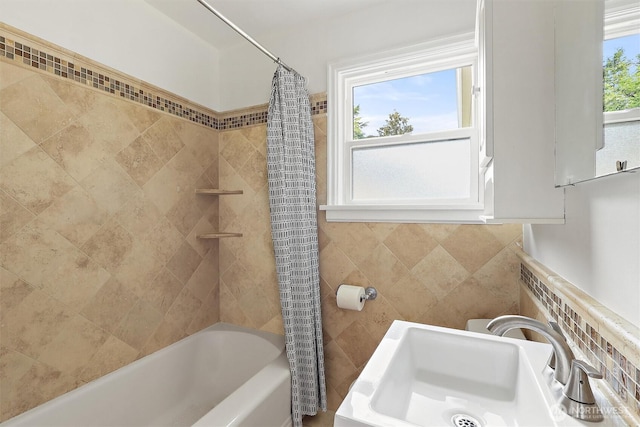 bathroom featuring a sink, tile walls, and shower / bath combination with curtain