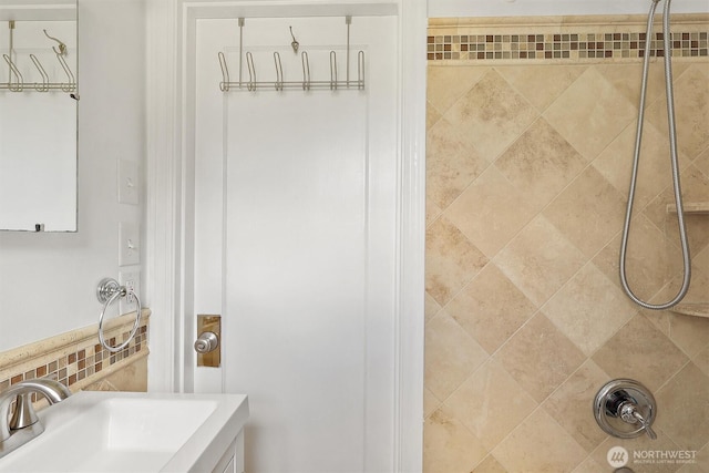 bathroom featuring a tile shower and a sink