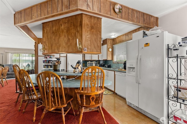 kitchen featuring a sink, light floors, white appliances, and a healthy amount of sunlight