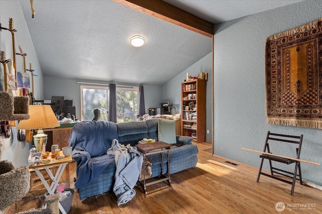 living room with a textured wall, a textured ceiling, and wood finished floors