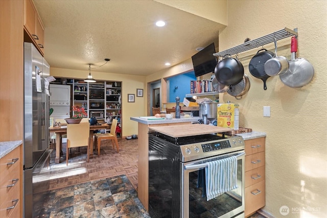 kitchen with appliances with stainless steel finishes, a textured wall, light countertops, recessed lighting, and brown cabinets