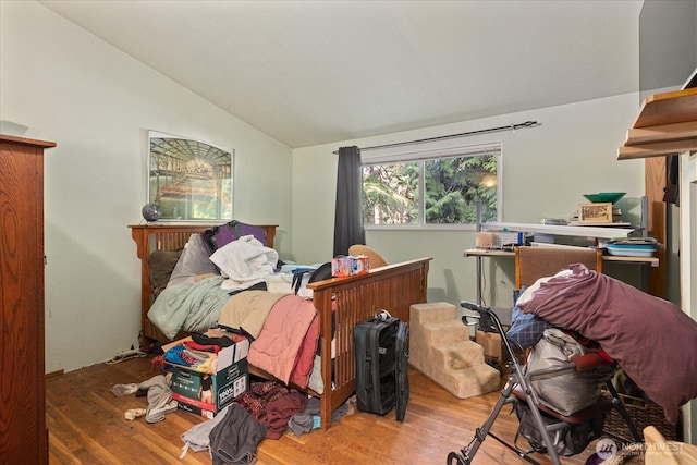 bedroom with vaulted ceiling and wood finished floors