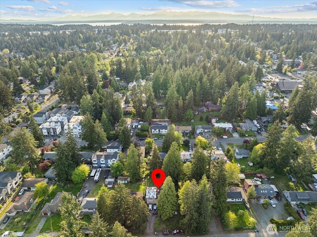 view of property location with nearby suburban area and a heavily wooded area