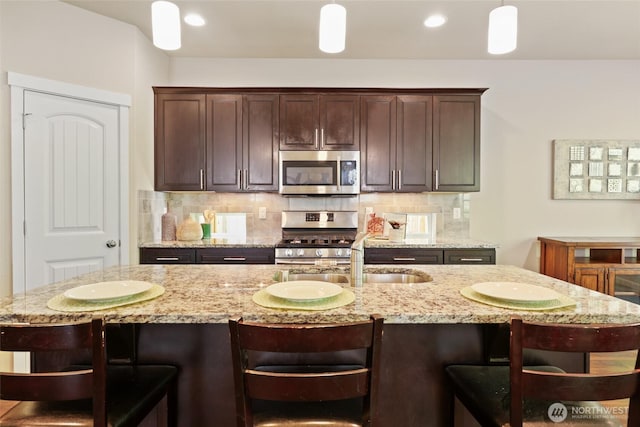 1517 Onyx St SE, Olympia, WA 98501 - kitchen featuring dark brown cabinets, a sink, tasteful backsplash, appliances with stainless steel finishes, and light stone counters