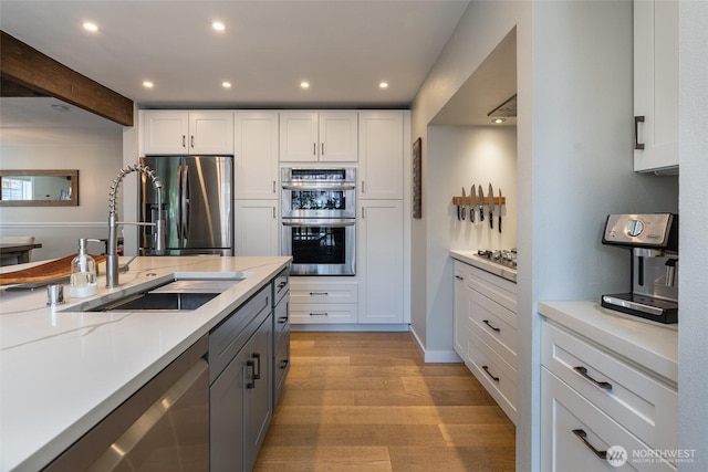 2656 168th Ave NE, Bellevue, WA 98008 - kitchen featuring stainless steel appliances, a sink, light wood-style floors, white cabinetry, and recessed lighting