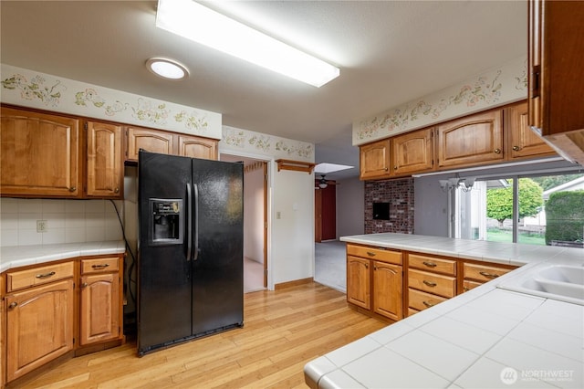 524 Carl Way, Aberdeen, WA 98520 - kitchen with black refrigerator with ice dispenser, tile countertops, light wood finished floors, brown cabinets, and backsplash