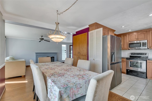 7351 32nd Ave SW, Seattle, WA 98126 - dining area with crown molding, ceiling fan, a fireplace, light wood-style floors, and recessed lighting