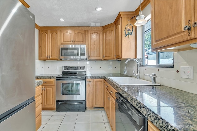 7351 32nd Ave SW, Seattle, WA 98126 - kitchen featuring stainless steel appliances, a sink, decorative backsplash, light tile patterned floors, and a textured ceiling
