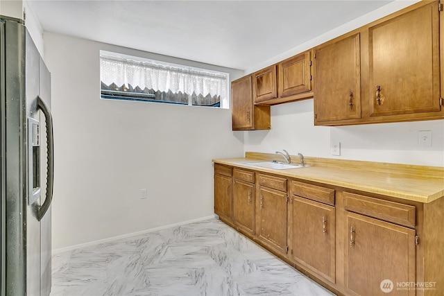 7351 32nd Ave SW, Seattle, WA 98126 - kitchen with stainless steel fridge, a sink, light countertops, and brown cabinets