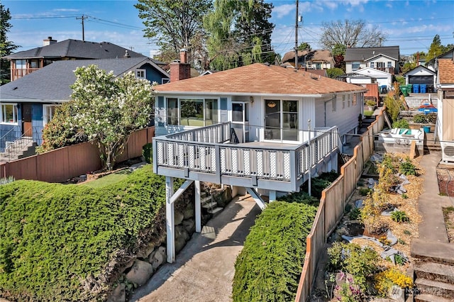 7351 32nd Ave SW, Seattle, WA 98126 - back of property featuring a residential view, a fenced backyard, a deck, a chimney, and roof with shingles