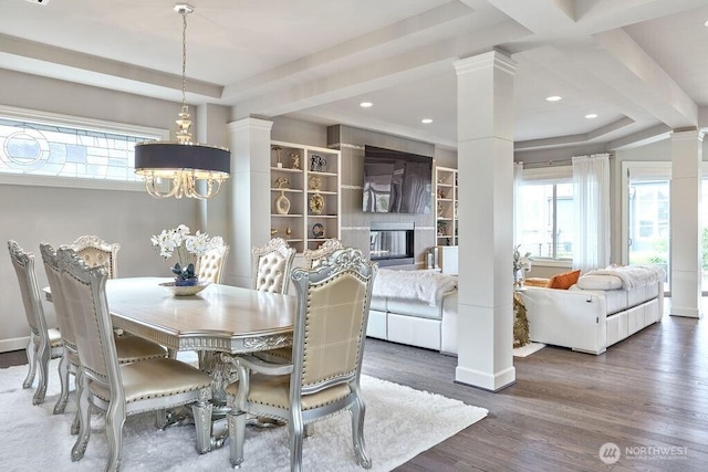 3319 Burnett Ave N, Renton, WA 98056 - dining area featuring ornate columns, a chandelier, a tray ceiling, wood finished floors, and a glass covered fireplace