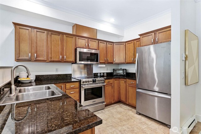 1015 Railroad Ave Unit 405, Bellingham, WA 98225 - kitchen with stainless steel appliances, a baseboard heating unit, a sink, brown cabinetry, and dark stone counters