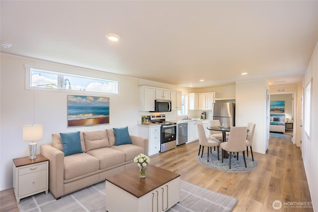 living area featuring a wealth of natural light, light wood-style floors, and visible vents