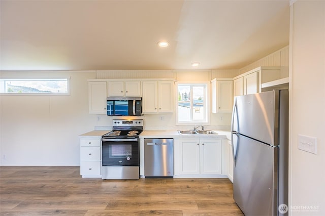 kitchen with light countertops, appliances with stainless steel finishes, white cabinetry, and a sink