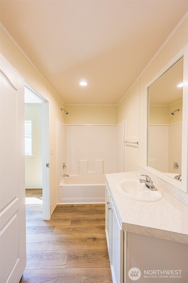 bathroom with recessed lighting, vanity, crown molding, shower / washtub combination, and wood finished floors