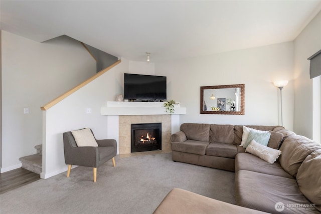 carpeted living room with stairs, a tile fireplace, and baseboards