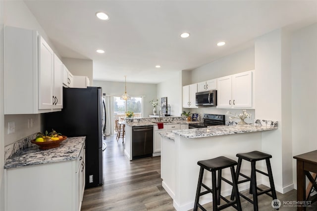 kitchen featuring appliances with stainless steel finishes, a peninsula, white cabinets, dark wood-style flooring, and recessed lighting