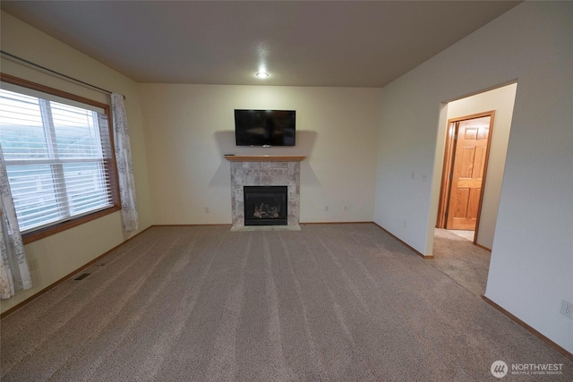 unfurnished living room featuring baseboards, carpet flooring, a tiled fireplace, and visible vents