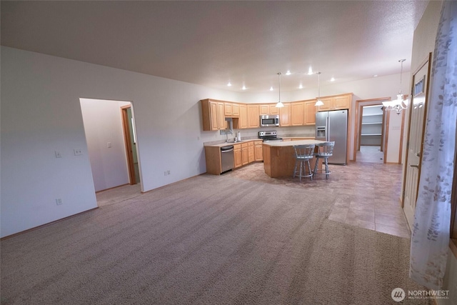 kitchen with a center island, a kitchen breakfast bar, pendant lighting, light countertops, and appliances with stainless steel finishes