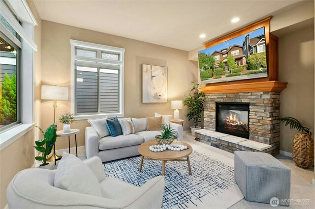 living area featuring a stone fireplace, plenty of natural light, baseboards, and recessed lighting