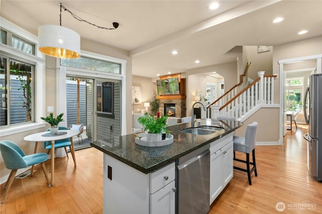 kitchen featuring appliances with stainless steel finishes, a sink, plenty of natural light, light wood finished floors, and recessed lighting