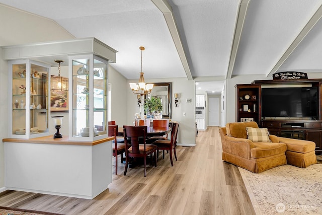living room featuring a chandelier, beamed ceiling, and light wood-style floors