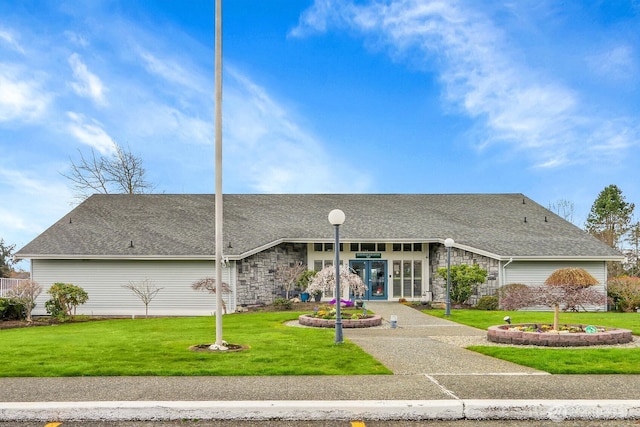 view of front of property with stone siding, roof with shingles, and a front lawn