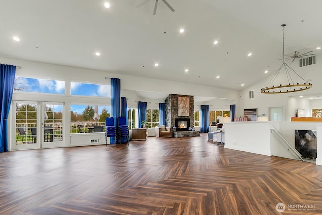 unfurnished living room featuring visible vents, a fireplace, a healthy amount of sunlight, and high vaulted ceiling