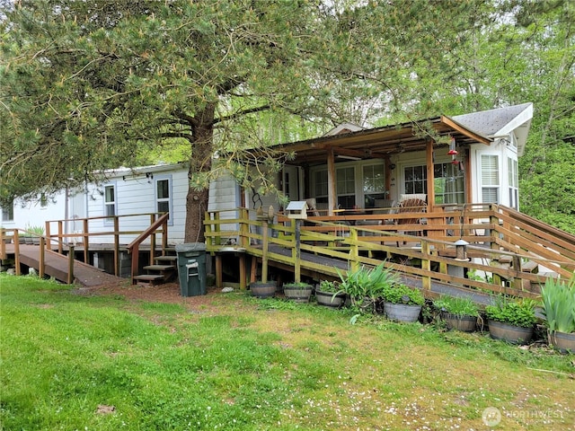 back of property featuring a wooden deck and a lawn