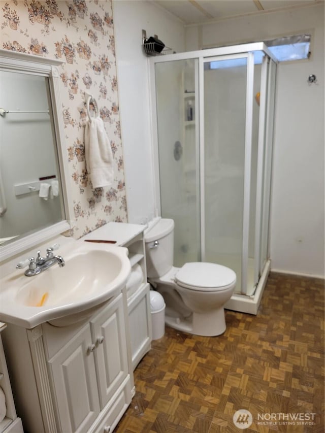 full bathroom featuring a stall shower, toilet, vanity, and wallpapered walls