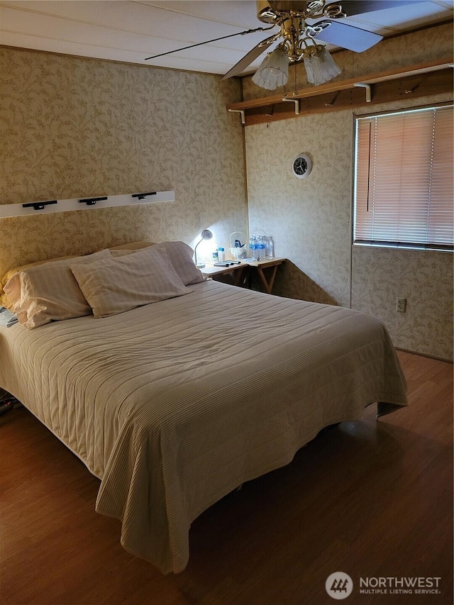 bedroom with wood finished floors, wallpapered walls, and ceiling fan