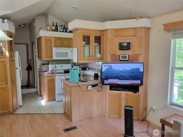 kitchen with white appliances, light wood-type flooring, glass insert cabinets, light countertops, and backsplash
