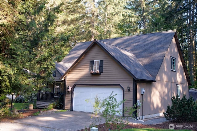 chalet / cabin with concrete driveway, a garage, and a shingled roof