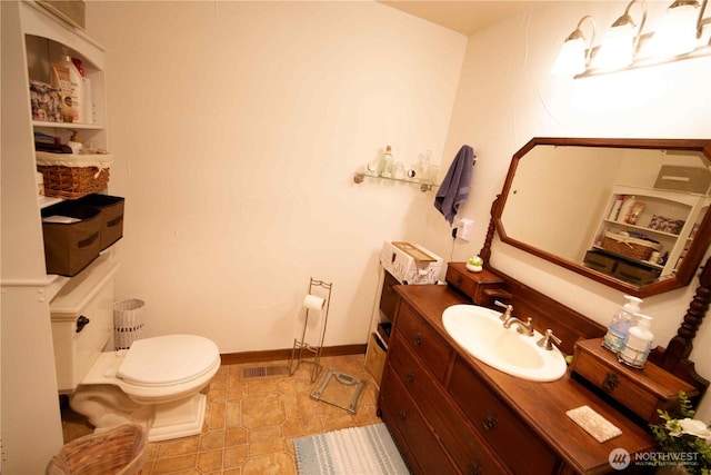 bathroom featuring toilet, vanity, and baseboards