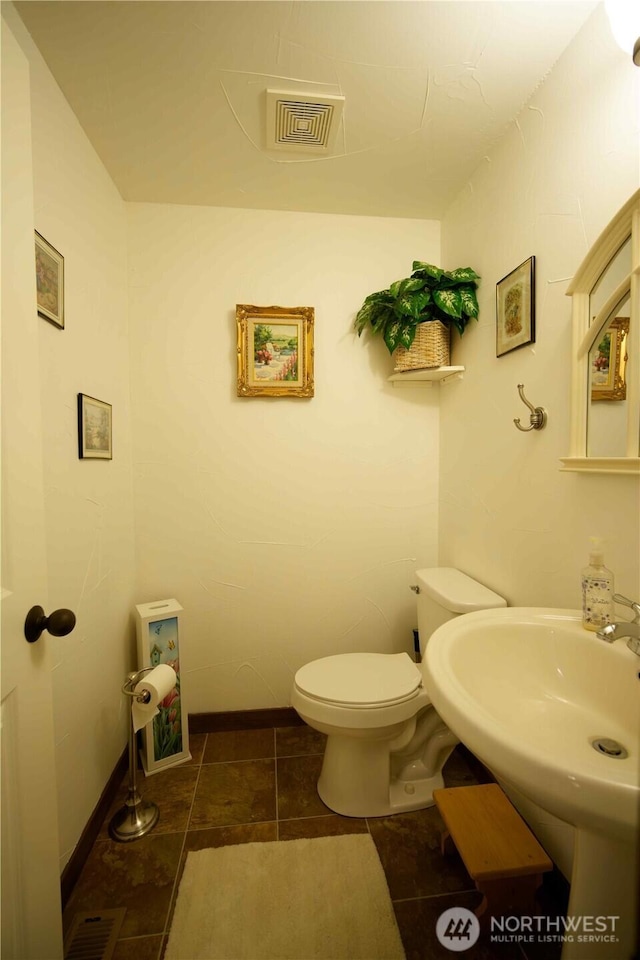 bathroom featuring toilet, baseboards, a sink, and tile patterned floors