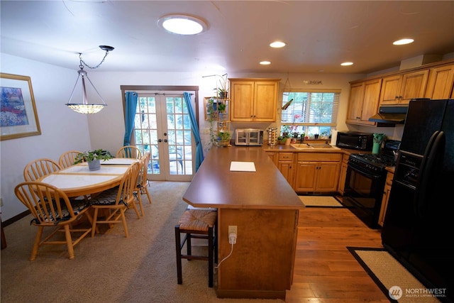 kitchen featuring black appliances, french doors, under cabinet range hood, a breakfast bar, and recessed lighting