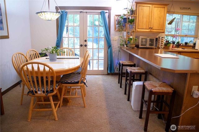 dining area featuring light carpet, french doors, healthy amount of natural light, and baseboards
