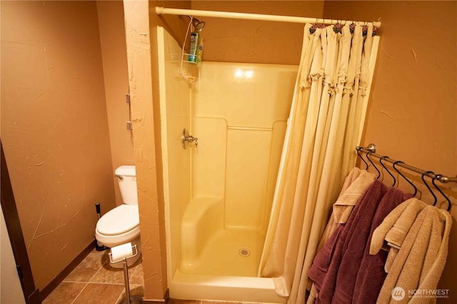 full bath with a stall shower, toilet, and baseboards