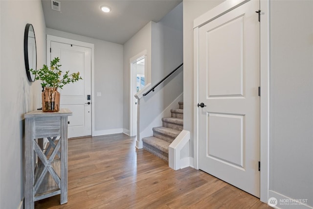 foyer with light wood-style floors, stairway, and baseboards