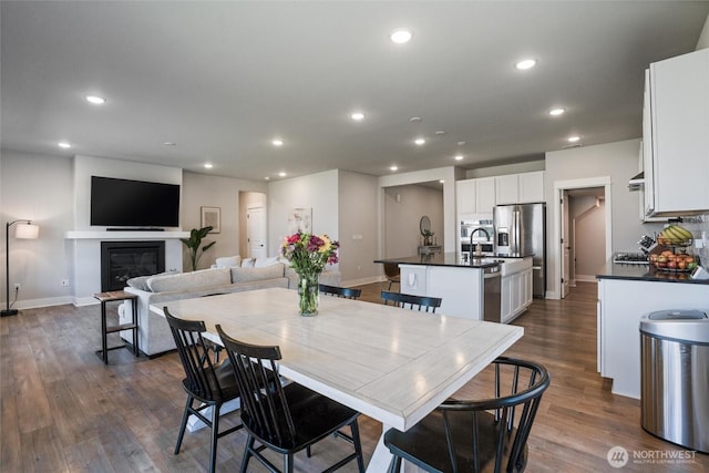dining room featuring recessed lighting, dark wood finished floors, baseboards, and a glass covered fireplace