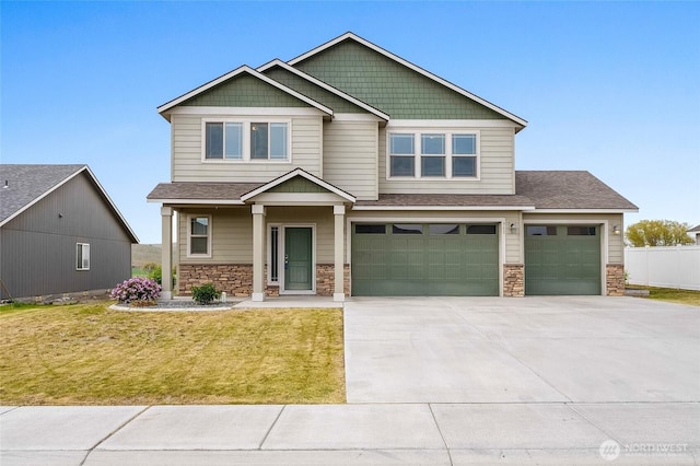craftsman-style home featuring fence, a garage, concrete driveway, stone siding, and a front lawn