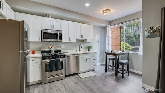 564 225th Ln NE Unit A-105, Sammamish, WA 98074 - kitchen with stainless steel appliances, a sink, light countertops, baseboards, and light wood-type flooring