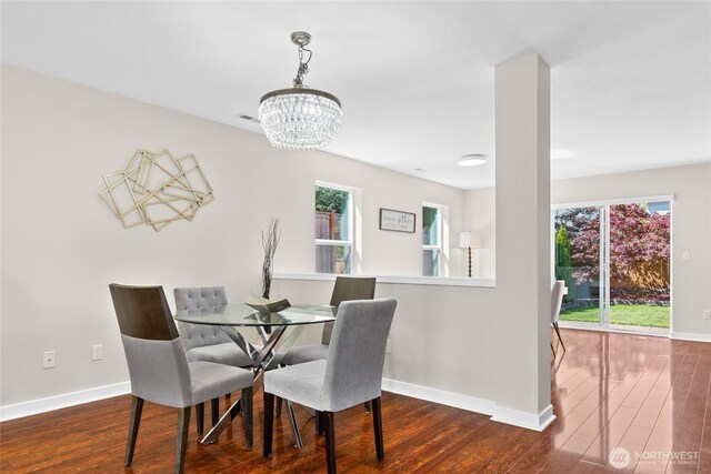 dining room featuring a chandelier, wood finished floors, and baseboards