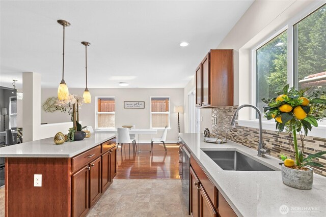 kitchen with a sink, brown cabinets, backsplash, healthy amount of natural light, and recessed lighting