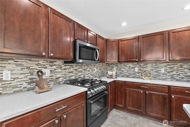 kitchen with black gas stove, stainless steel microwave, light countertops, tasteful backsplash, and recessed lighting