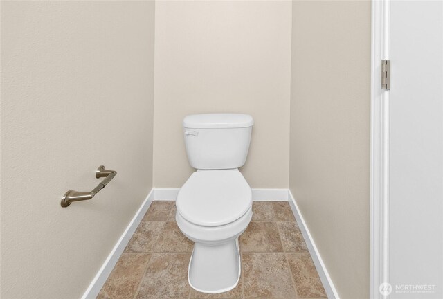 bathroom with toilet, baseboards, and tile patterned flooring